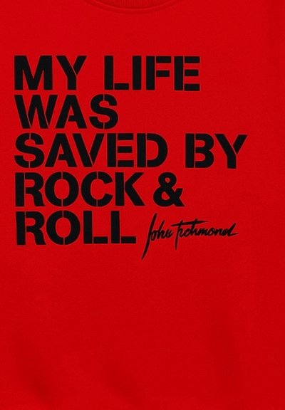 T-shirt rossa con il bold del testo nero che recita "LA MIA VITA È STATA SALVATA DAL ROCK & ROLL" e una firma, su una superficie di tessuto liscia.