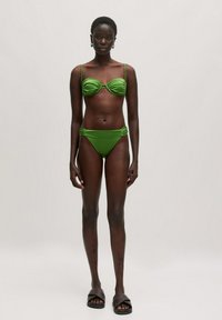 Groene bikini-set met een geraffineerde top met dunne bandjes en een hooggesneden broekje. Glad materiaal met een minimalistisch ontwerp.