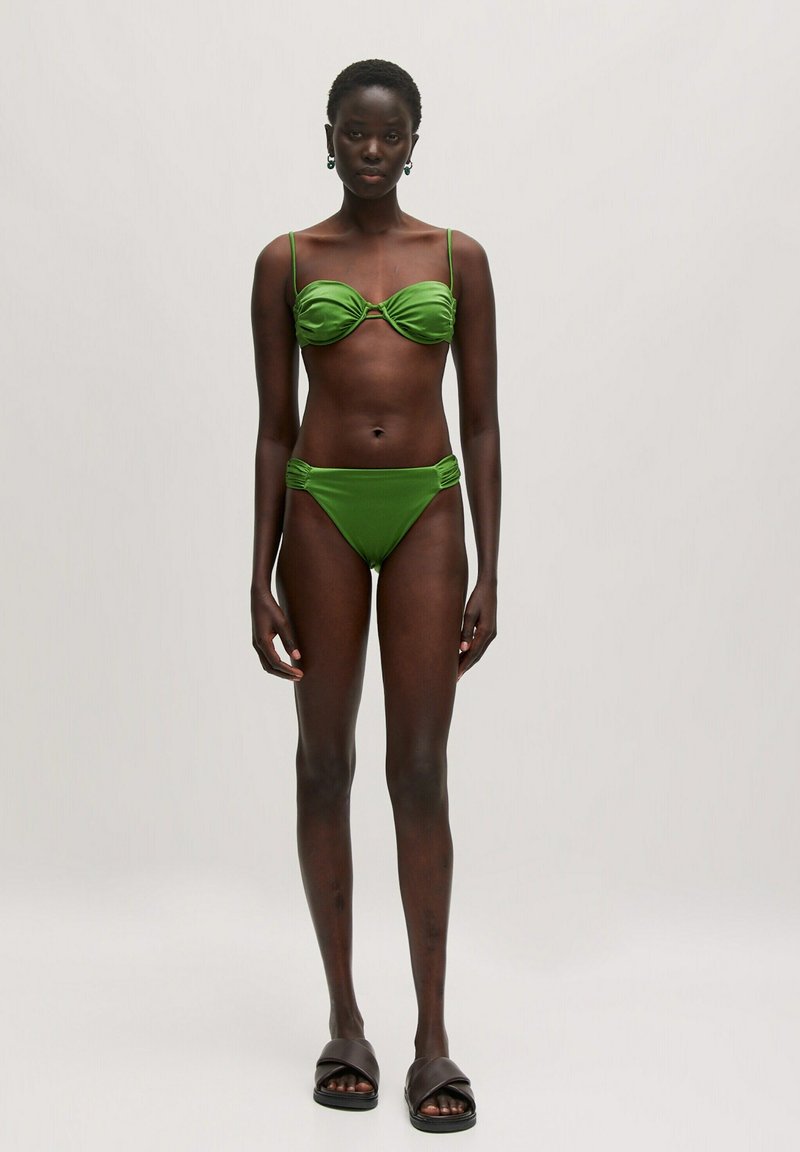 Groene bikini-set met een geraffineerde top met dunne bandjes en een hooggesneden broekje. Glad materiaal met een minimalistisch ontwerp.
