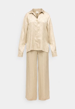 Camisa de botão de manga longa em seda bege com colarinho e calças largas a condizer, ambos com um padrão geométrico subtil.