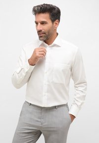 Witte overhemdd met een borstzak, lange mouwen en een gladde textuur, gecombineerd met lichtgrijze pantalon.