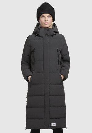 Black puffer coat with a knee-length design, featuring a high collar, two zip pockets, and a logo patch at the hem. Textured fabric with quilted pattern.