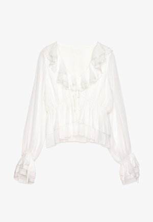 White blouse with ruffled neckline and cuffs, featuring a cropped design, textured fabric, and adjustable ties at the front and sleeves.