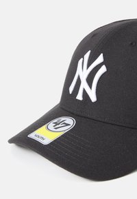 Svart baseballcaps med hvit brodert "NY"-logo, laget av bomull, med buet brem og en størrelseslapp som angir ungdomsfit.