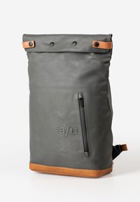 Gray backpack with a roll-top design, featuring a smooth texture, black zipper, and brown leather accents at the base and snaps.
