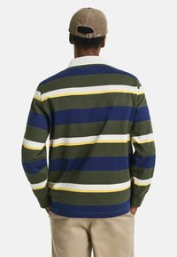 Camisa polo de manga larga con rayas horizontales en verde, azul marino, blanco y amarillo; material de algodón; cuello acanalado; corte relajado.