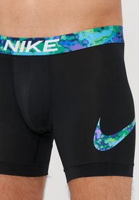 Zwarte Nike boxershorts met een veelkleurige, abstracte elastische band en een bijpassend blauw en groen logo op de zijkant. Rekbare stof.