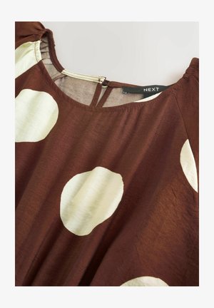 Ruda audinio palaidinė su didelėmis kreminėmis taškelėmis, su apvalia iškirpte ir užpakalinį raktelio formos plyšį. Medžiaga turi lygią faktūrą.