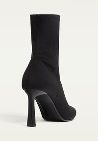 Stivali neri alla caviglia con un design elegante, tomaia in tessuto, punta affusolata, alto tacco a stiletto e dettagli di cucitura visibili lungo le cuciture.