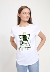 Bílý tričko s krátkým rukávem, na kterém je zeleno-černá grafika znázorňující stojící postavu v taktickém vybavení, která drží zbraň, na pozadí zelených geometrických tvarů.