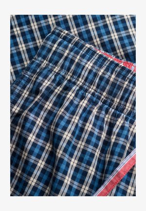 Tessuto a quadretti blu e bianco con fascia elastica in vita e bordatura a righe rosse, bianche e blu lungo il bordo.