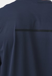 Tissu bleu foncé avec un motif texturé subtil comportant une fine bande noire horizontale sur le haut du dos.