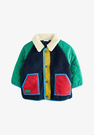 Chaqueta colorida con un cuerpo de piel de oveja azul, mangas acolchadas verdes, panel frontal amarillo y bolsillos rojos con ribete azul. Cuello de sherpa.