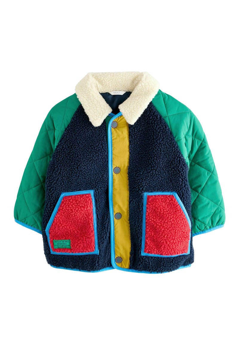 Veste colorée avec un corps en polaire marine, des manches matelassées vertes, un panneau avant jaune et des poches rouges. Dotée d'un col en peluche blanche.