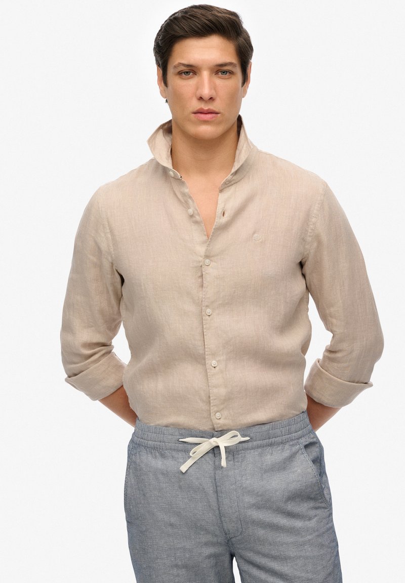Lichtbeige linnen overhemd met een knoopsluiting bij de kraag en opgerolde mouwen, met een subtiele textuur en een klein geborduurd logo.