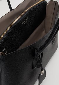 Borsa a tracolla in pelle nera testurizzata con cerniera superiore, interno beige, due scomparti e dettagli in metallo dorato.