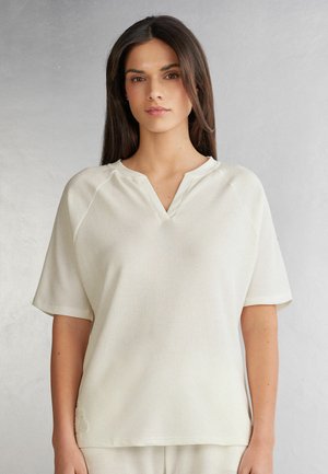 Lichtbeige kortärmelige top met een v-hals en een gestructureerde ribstof. Bevat raglanmouwen en een ontspannen pasvorm.
