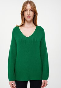 Grüner Strickpullover mit tiefem V-Ausschnitt, geripptem Textur und langen Ärmeln. Verfügt über eine lockere Passform und horizontale Rippmuster.