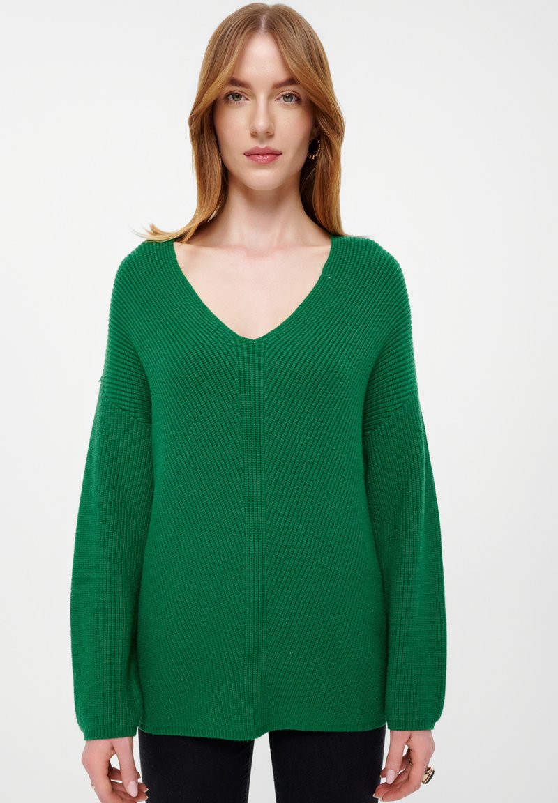 Grüner Strickpullover mit tiefem V-Ausschnitt, geripptem Textur und langen Ärmeln. Verfügt über eine lockere Passform und horizontale Rippmuster.