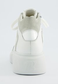 Baskets blanches avec une tige en cuir lisse et en daim, dotées d'une semelle plateforme texturée et d'une fermeture éclair à l'arrière. Logo embossé sur le talon.