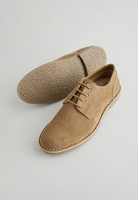Light brown suede shoes with a classic design, featuring a lace-up front, stitched accents, and textured rubber sole.