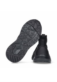 Zwarte sportschoenen met een gestructureerde rubberen zool met een driehoekig patroon en een lus aan de achterkant voor gemakkelijk aan- en uittrekken.