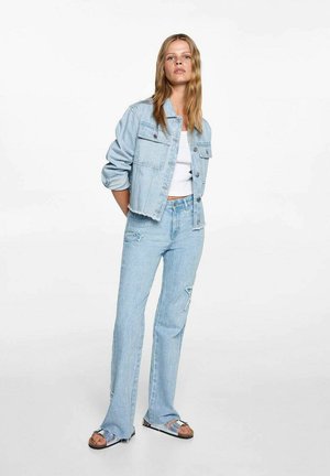Helle blaue, verkürzte Denim-Jacke mit zwei Vorderaschen, kombiniert mit hellblauen, ausgefransten Schlaghosen und braunen Sandalen.