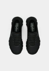 Schwarze Slipper mit strukturiertem Obermaterial, elastischen Schnürsenkeln, gepolstertem Kragen und robustem Profil für guten Grip. Markenlogo auf den Innensohlen sichtbar.