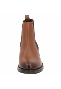 Botín Chelsea de cuero marrón con paneles laterales elásticos, punta redondeada y tirador. Textura suave con un ligero brillo. Suela negra con agarre.