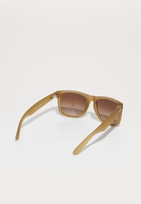 Ochelari de soare mat cu ramă pătrată, lentile maro cu gradient și textură netedă. Prezentă un hardware din metal și brațe alungite pentru o ajustare sigură.