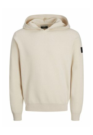 Beige hoodie met een gladde textuur, ribbelboorden en -zoom, en een klein zwart logo patch op de linkermouw.