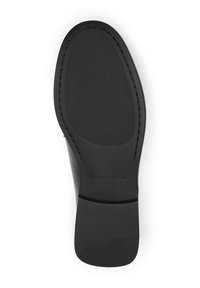 Black shoe sole with textured grip, rounded shape, and slight heel. Features raised logo and stitching along the edge. Size marked as 37.