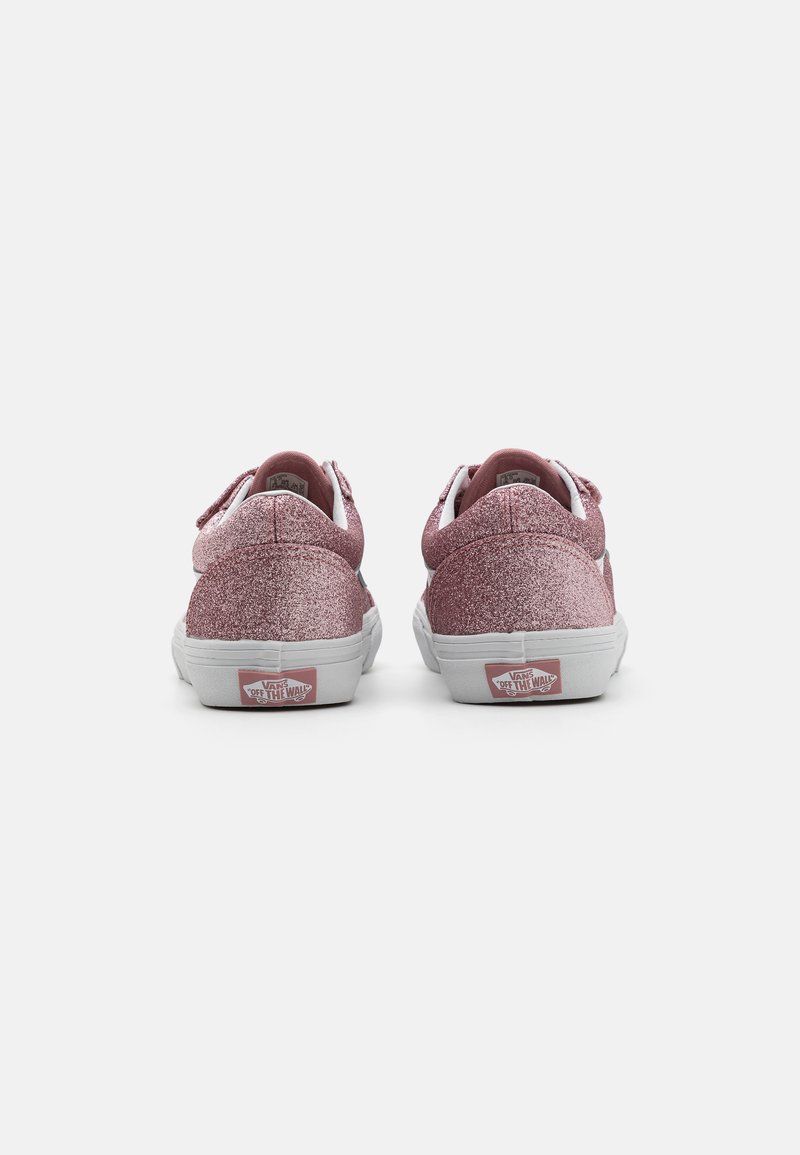 Sneakers glitterati rosa con suole in gomma bianche, caratterizzati da un design a basso profilo, lacci bianchi a contrasto e un logo sul tallone.