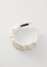 Hvit stoffhodebånd med vridd design og strukturert overflate. Har et merke på innsiden. Glatt og fleksibelt materiale.