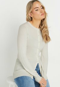 Ljusbeige cardigan i mjukt stickat material. Har rund halsringning, helärmade ärmar och knappstängning fram.