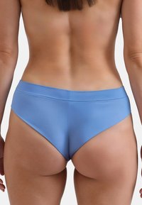 Slip da bagno blu con una texture liscia, caratterizzati da un design a vita alta che mette in risalto la vita e le gambe. Cuciture minime e linee pulite.