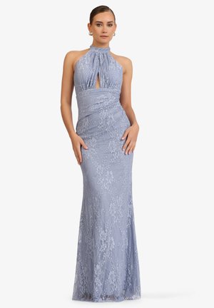 Frau präsentiert ein ärmelloses, bodenlanges Lavendelfarbenes Spitzenkleid mit Neckholder und Frontschlüssellochausschnitt, steht mit den Händen nahe den Hüften.