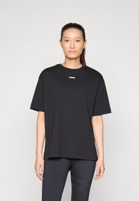 Svart oversized t-skjorte laget av bomull, med korte ermer og rund halslinning. "STRONGER" logo i hvitt på brystet.