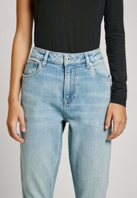 Lichtblauwe denim jeans met een hoge taille, vijf-pocket ontwerp en subtiele vervaging. Bevat een rits en een enkele metalen knoopsluiting.