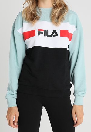 Sweat-shirt à manches longues FILA avec un design en blocs de couleurs : sections blanches, rouges et noires. Tissu doux et texturé, poignets et taille côtelés.