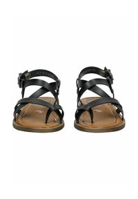Černé kožené sandály se zkříženými pásky a přezkou. Podešev je hnědá s prošívaným okrajem, což poskytuje kontrast v barvě a textuře.