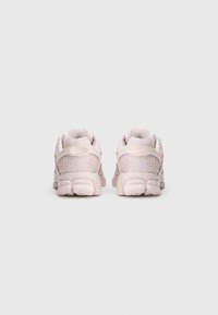 Scarpe sportive rosa con tomaia in rete, colletto imbottito e dettaglio testurizzato sul tallone. La suola presenta un design cuscinetto e segmentato per un adeguato supporto.