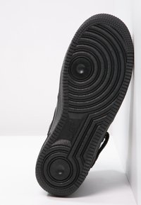 Czarna podeszwa trampka z okrągłymi wzorami i teksturowanym uchwytem, z gładkim wykończeniem i wyraźnie zaokrąglonymi sekcjami dla lepszej przyczepności.