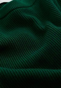 Donkergroene gebreide stof met een geribbelde textuur, met variërende tinten en een zachte, iets rekbare uitstraling.