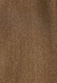 Tissu marron présentant une surface douce et texturée avec de fines fibres et une finition mate uniforme. Aucun motif ni détail notable présent.