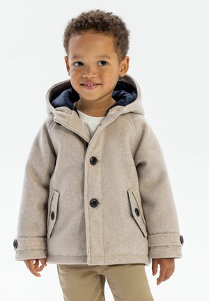 Chaqueta con capucha beige hecha de una tela suave, con botones negros, dos bolsillos laterales y un forro interior azul marino.