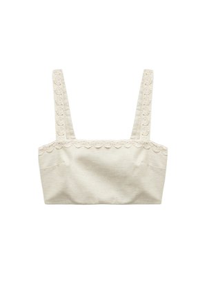 Débardeur beige raccourci avec de larges bretelles et une bordure décorative en dentelle florale le long de l'encolure et des bretelles.