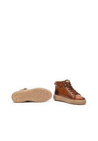 Baskets montantes en cuir marron avec une semelle en caoutchouc beige, des lacets contrastants et un talon renforcé. Motifs texturés sur la semelle.