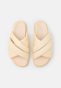 Korsade flip-flops i mjukt gult material med en slät yta. Har en vadderad sula och präglad märkning i silver.