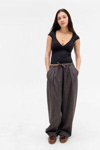 Black fitted top with short sleeves, paired with gray pinstriped wide-leg trousers featuring an elastic waistband and side pockets. Brown loafers.